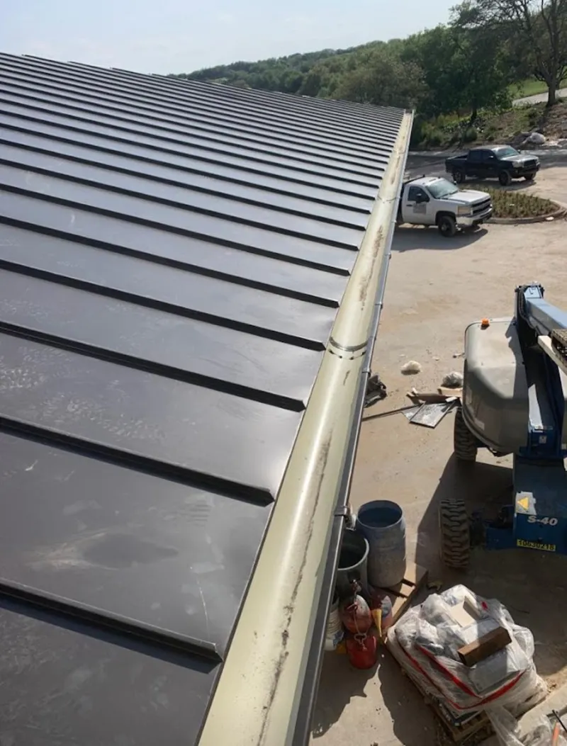Standing seam panel and gutter detail on a metal roofing jobsite in Tipton